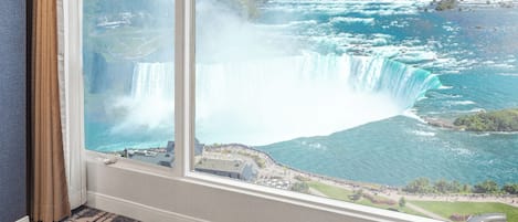 Una habitación con un amplio ventanal que da a una cascada y una extensión de agua.