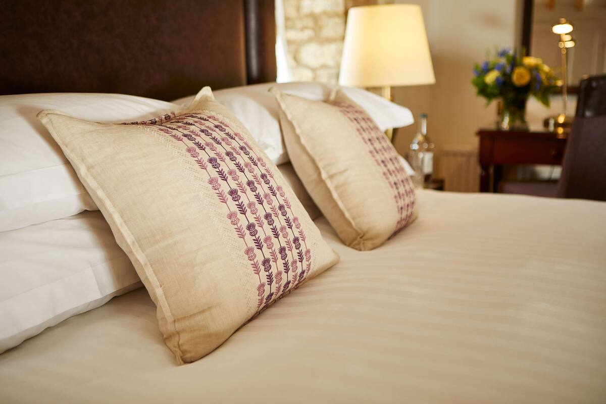 A neatly made bed with beige pillows and a white comforter.