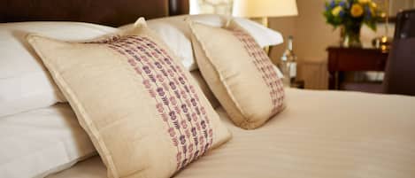 A neatly made bed with beige pillows and a white comforter.