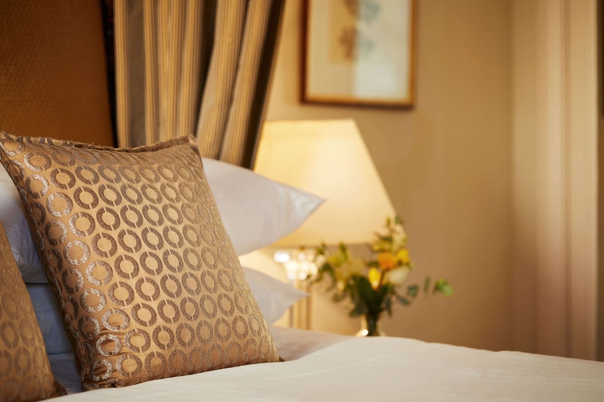 A neatly made bed with patterned pillows and a bedside lamp.