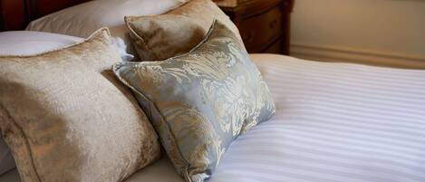 Una cama con dos almohadas, un cabecero de madera y una mesita de noche con una vela.