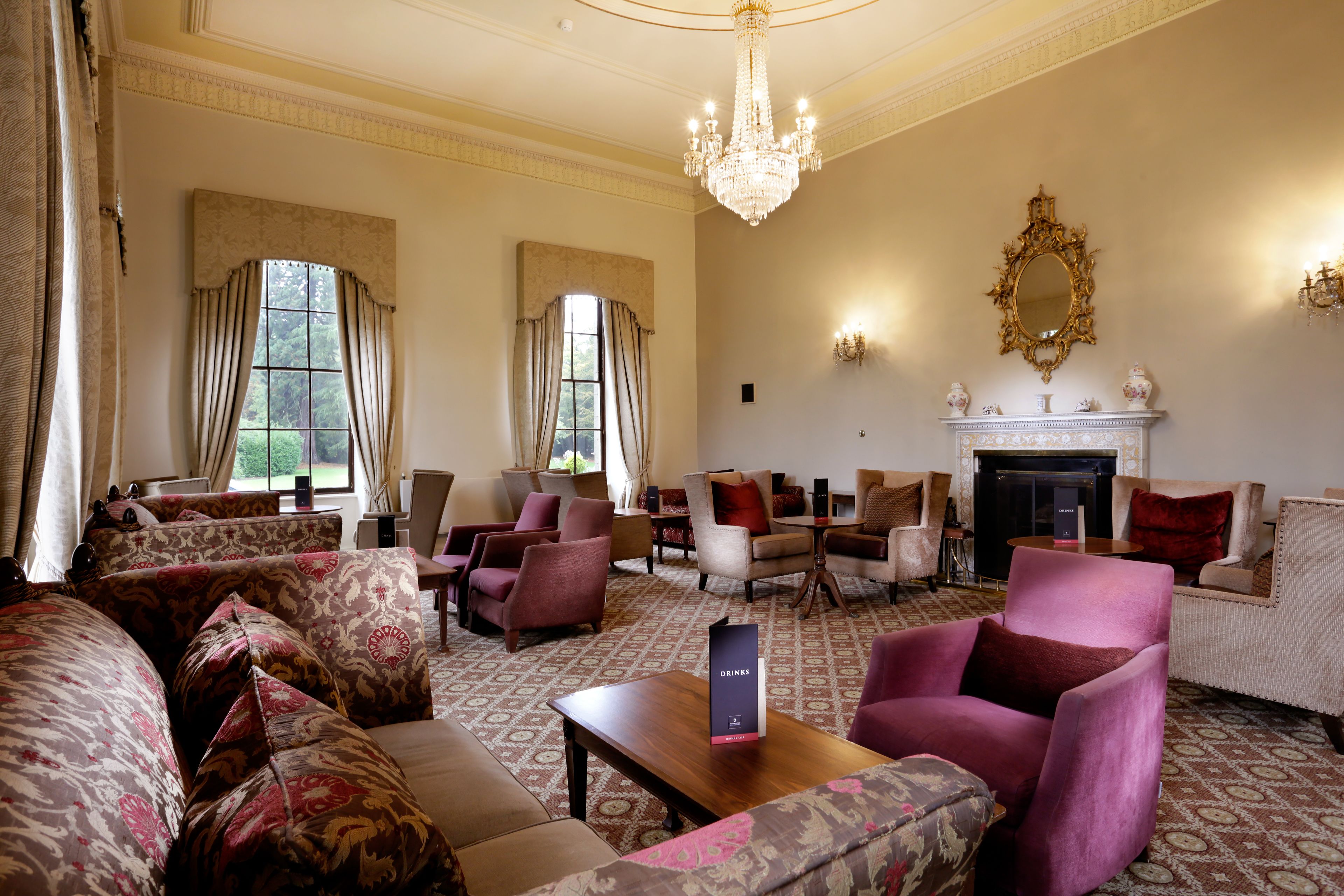 A spacious lounge with comfortable seating, a fireplace, and large windows providing natural light.