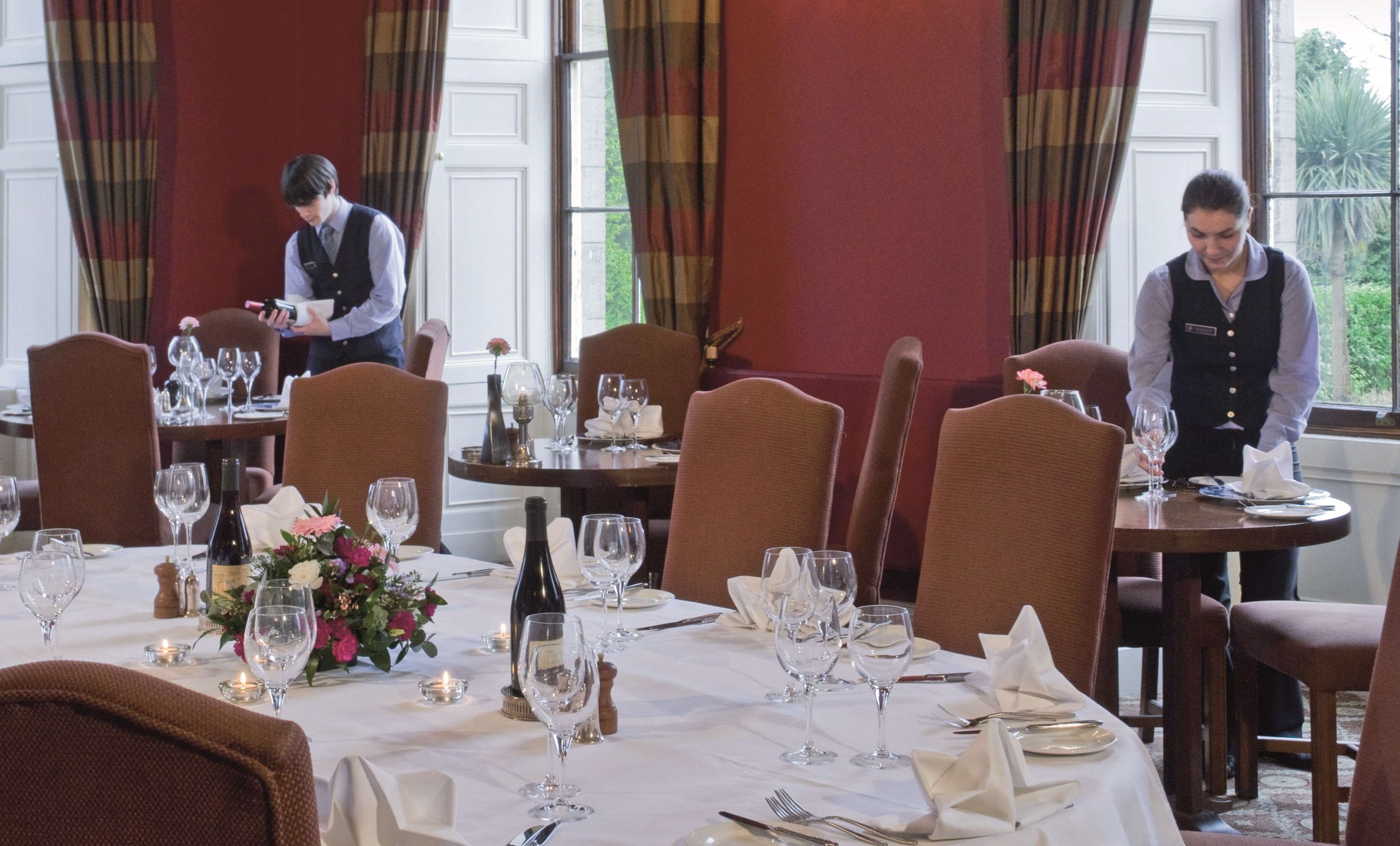 A dining area with tables set for a meal, including wine glasses, plates, and cutlery.