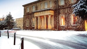 A large, historic building with a symmetrical facade, columns at the entrance, and a snow-covered street in front. - Macdonald Linden Hall Golf & Country Club (Morpeth)