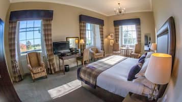 Hotelkamer met een groot bed, een bureau met een computer, een stoel, een televisie en uitzicht op de omgeving.