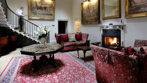 A spacious living room with a fireplace, ornate furniture, and large paintings on the walls. - Macdonald Linden Hall Golf & Country Club (Morpeth)