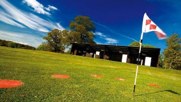 A building with a flagpole, surrounded by a grassy field and trees.
