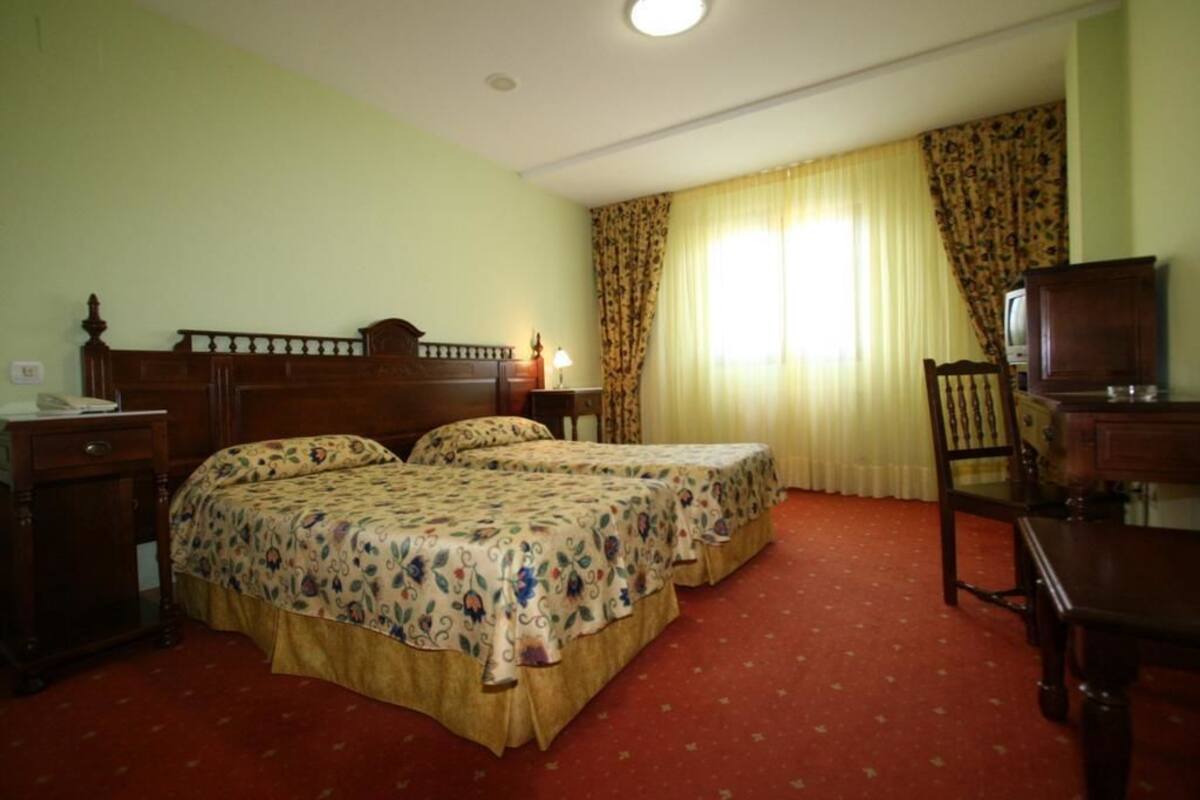 Een hotelkamer met twee bedden, een bureau, een stoel en een televisie.