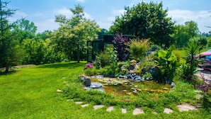 A lush garden with a pond, surrounded by various plants and trees. - Hotel Cueli (Santillana del Mar)
