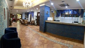 A hotel lobby with a reception desk, seating area, and a chandelier. - Hotel Cueli (Santillana del Mar)