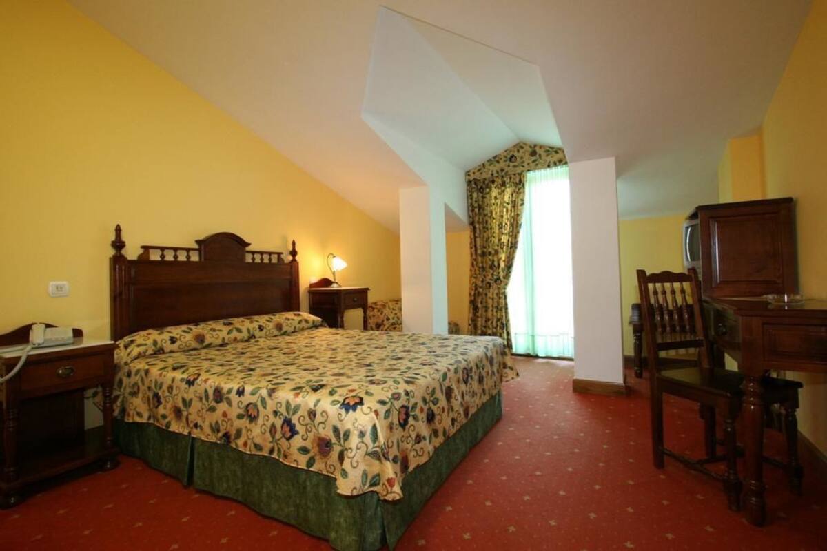 Een slaapkamer met een groot bed, een bureau, een stoel en een nachtkastje.