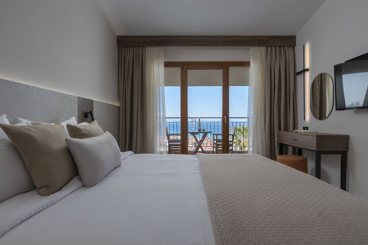 Une chambre d’hôtel avec un grand lit, un bureau, une chaise et un balcon avec vue.