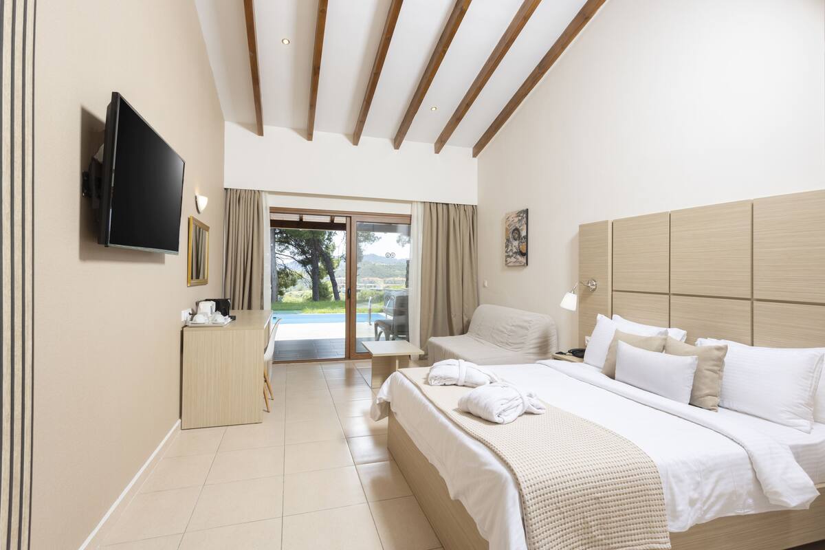 Une chambre d’hôtel équipée d’un lit, d’un bureau, d’une télévision et offrant une vue sur l’extérieur.