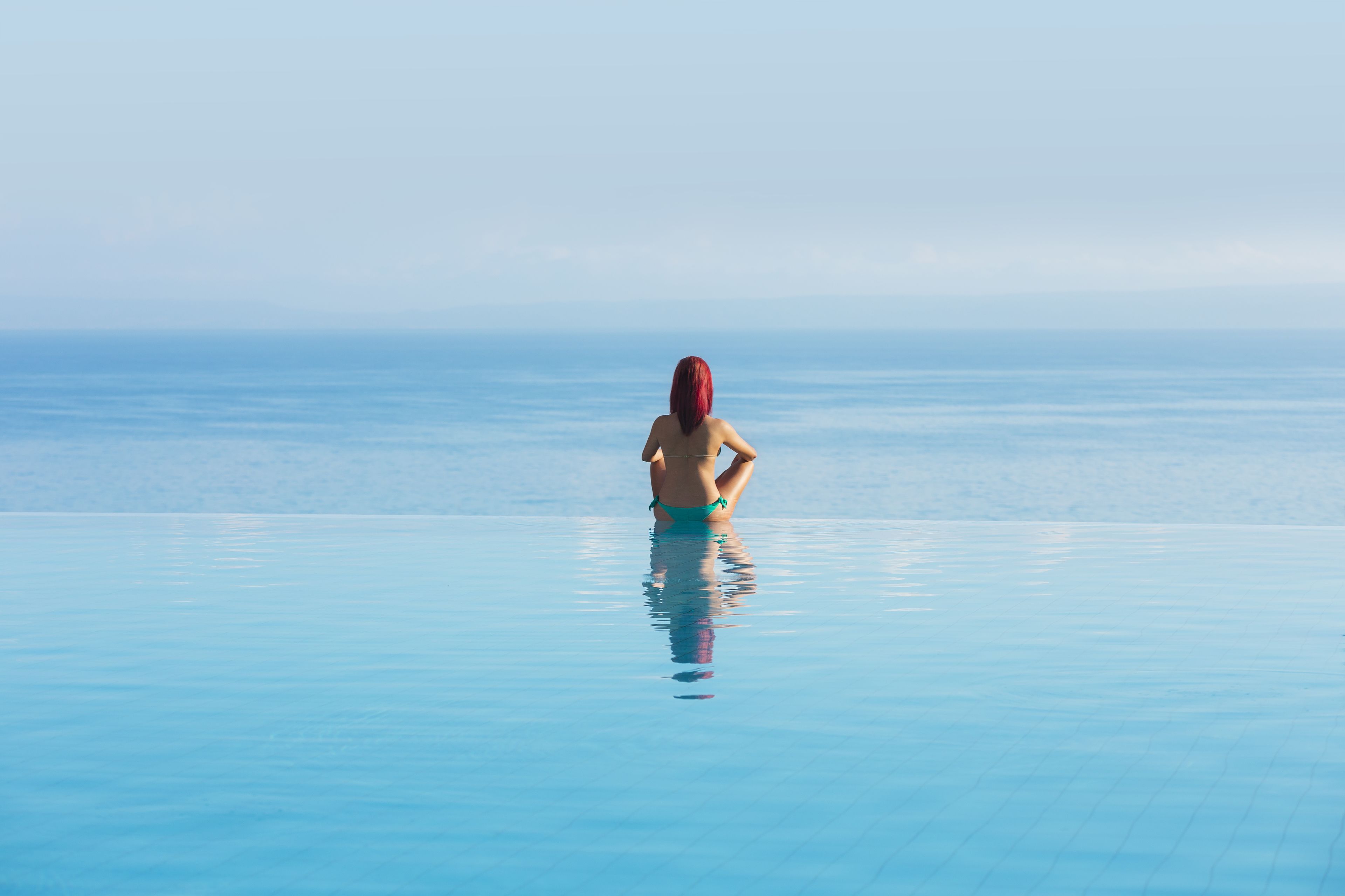 Una persona in piedi in una piscina cristallina con vista sull'orizzonte.