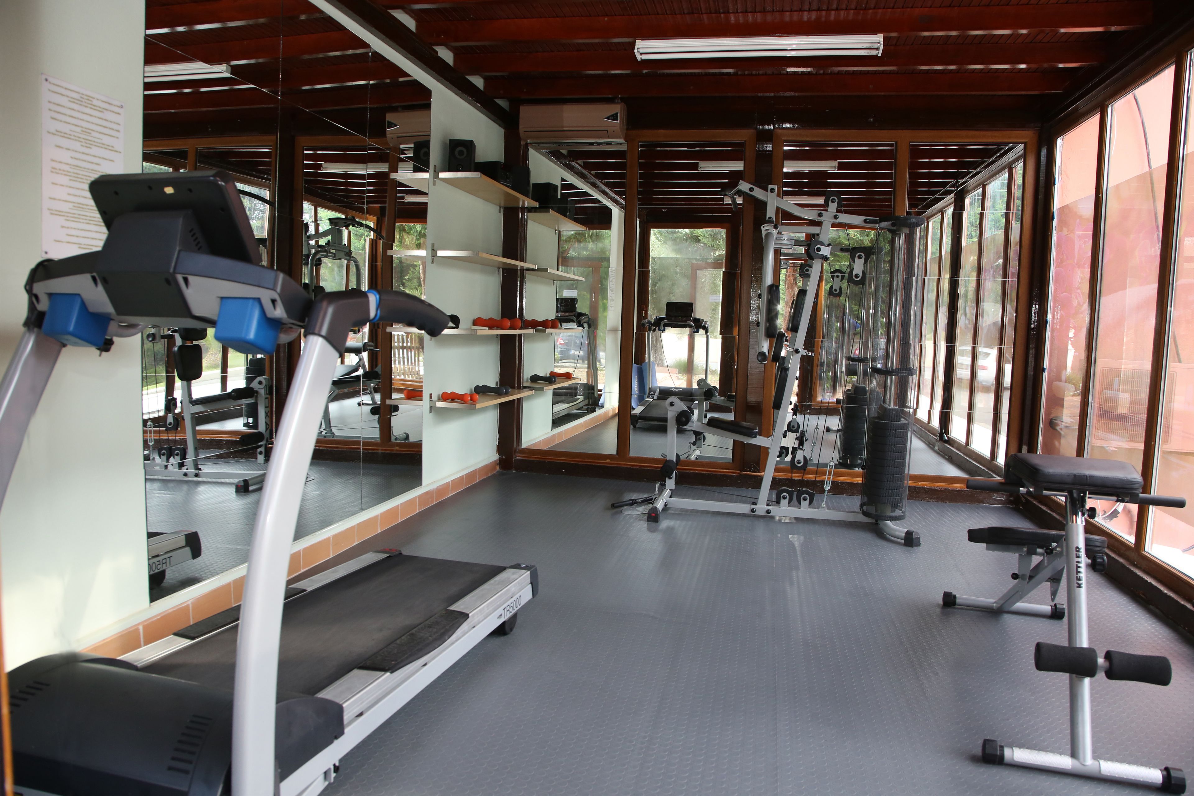 Une salle de sport équipée de tapis de course, d’appareils de musculation et de bancs.