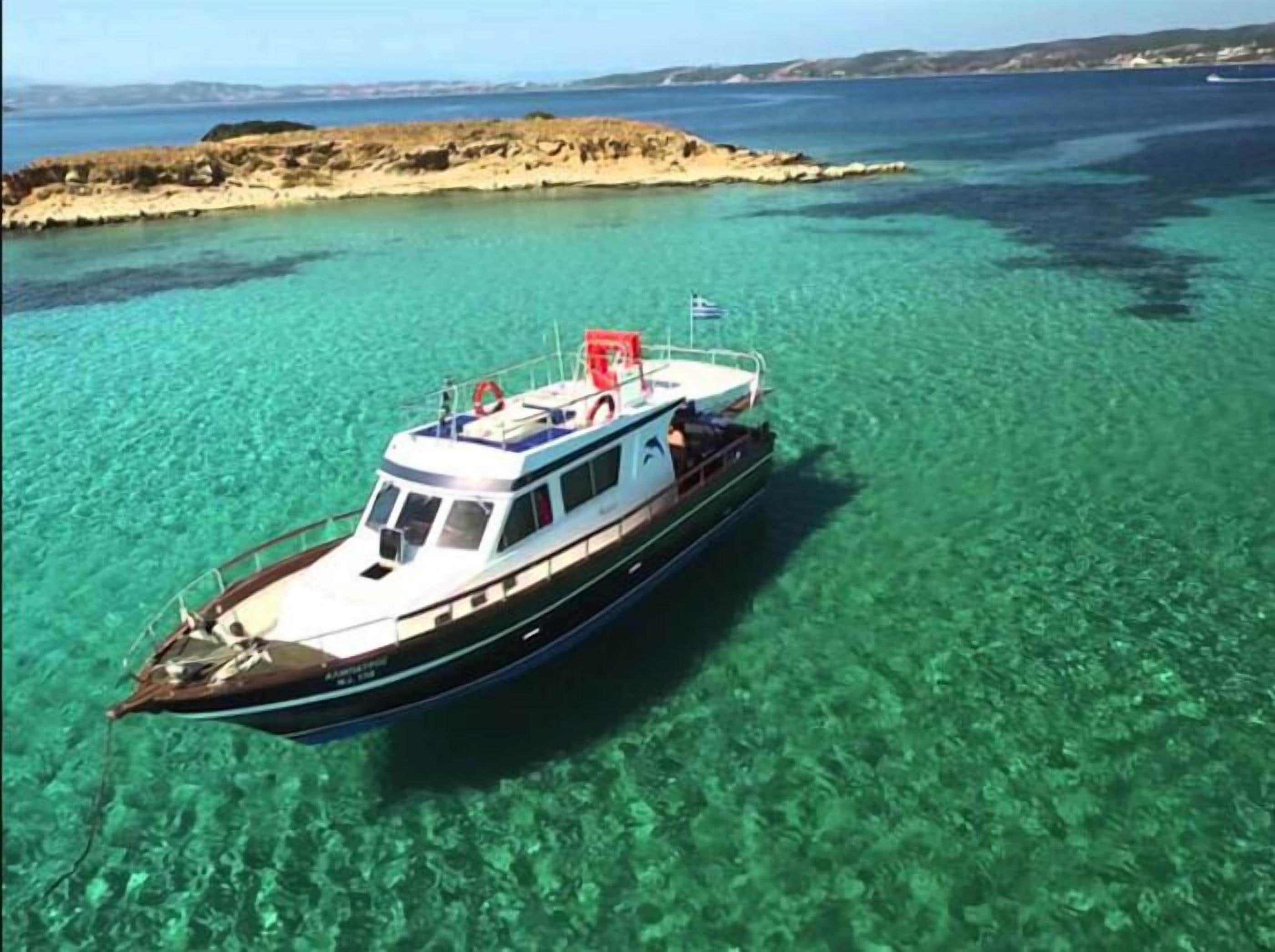 Un bote con cabina y zona de cubierta, flotando sobre aguas turquesas cristalinas.
