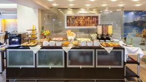 Montaje de bufé con diversos alimentos y una máquina de café.