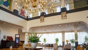 Eine geräumige Lobby mit hoher Decke, einem imposanten Kronleuchter und mehreren Sitzbereichen.