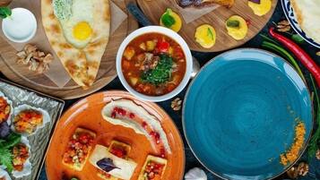 Diversos pratos, incluindo pães achatados, uma tigela de sopa e um prato com molho vermelho e legumes.