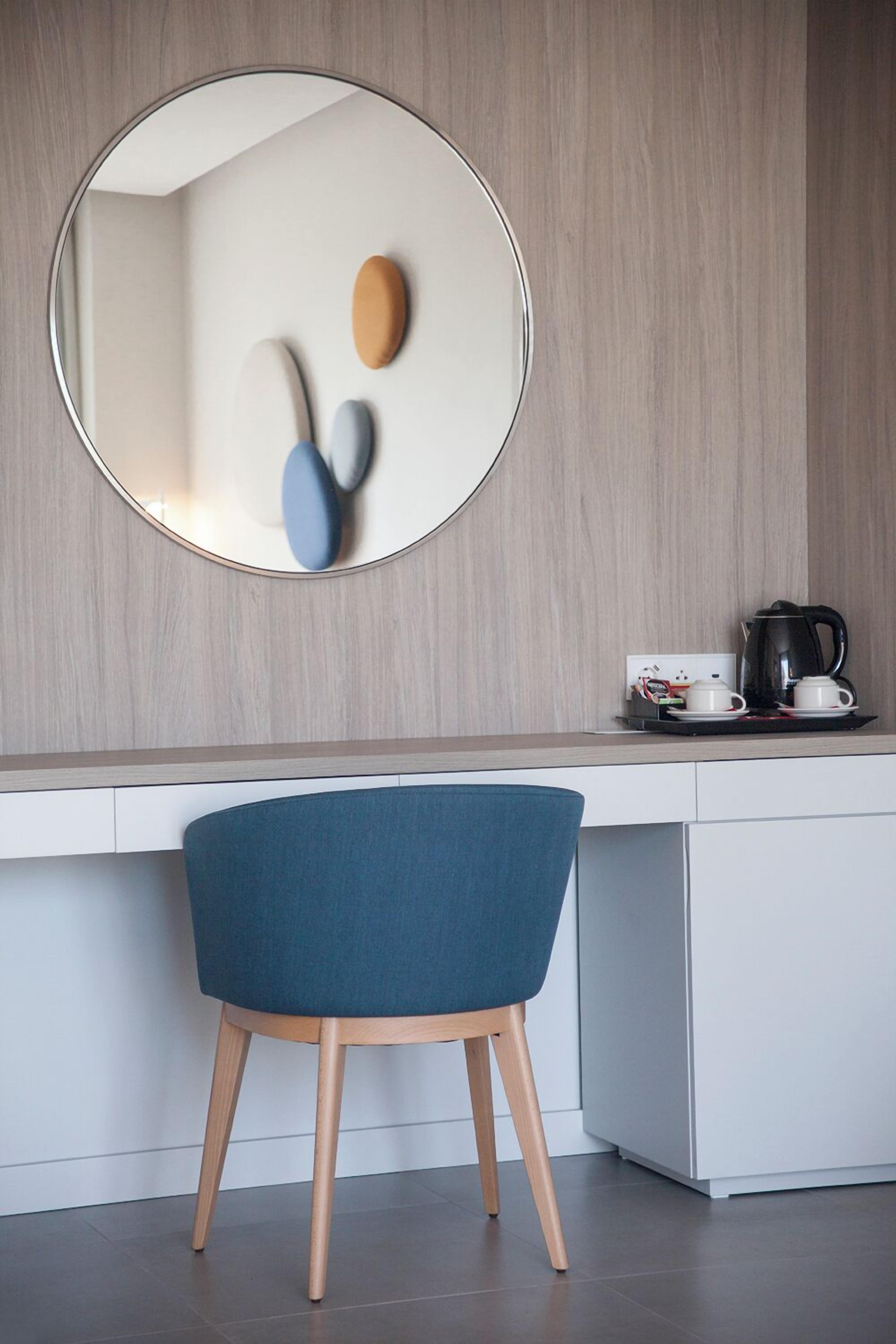 Una cocina moderna con un espejo redondo, una silla azul y una cafetera sobre la encimera.