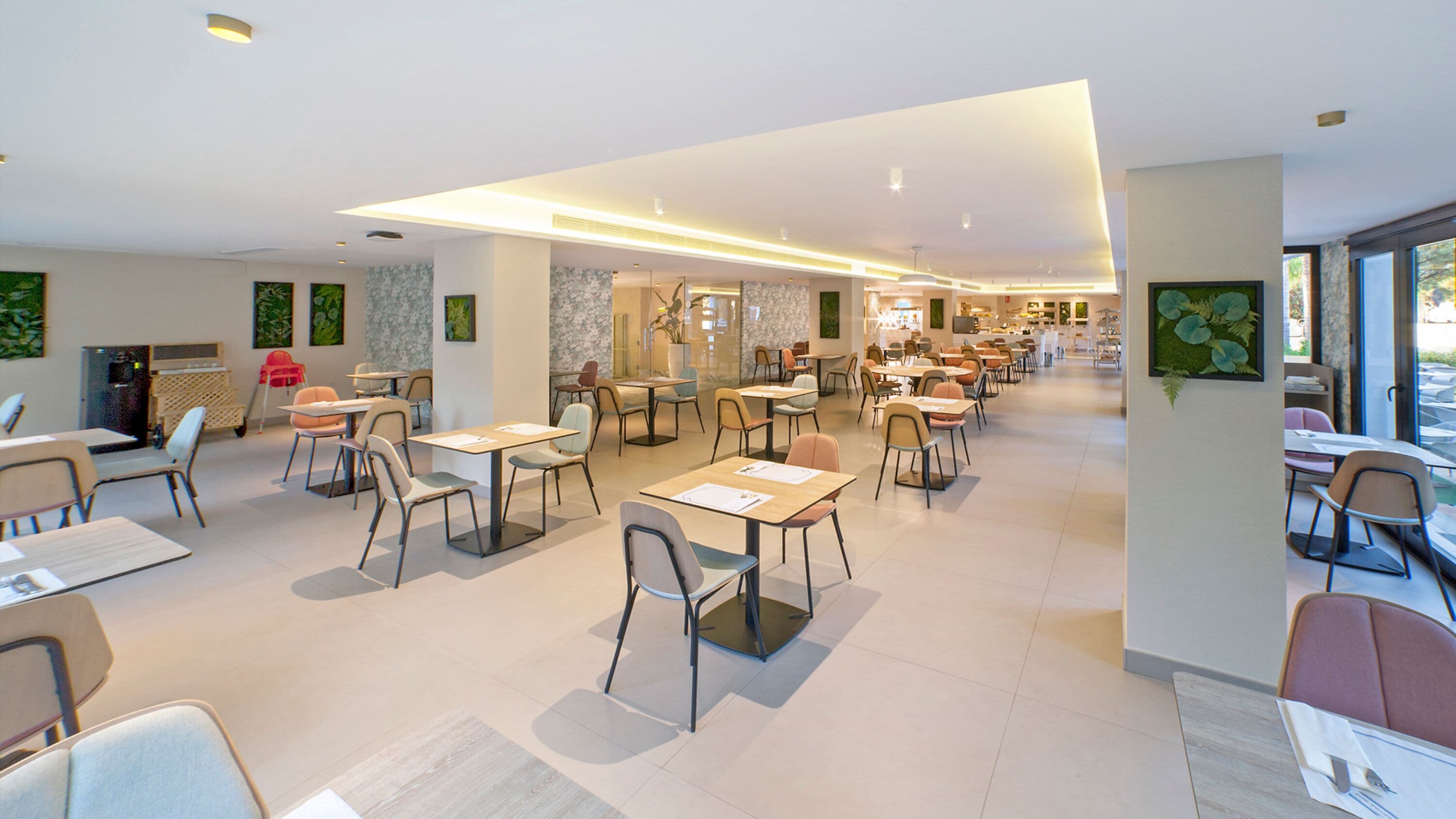 Een ruim restaurant met meerdere tafels en stoelen, een modern interieur en grote ramen voor natuurlijk licht.
