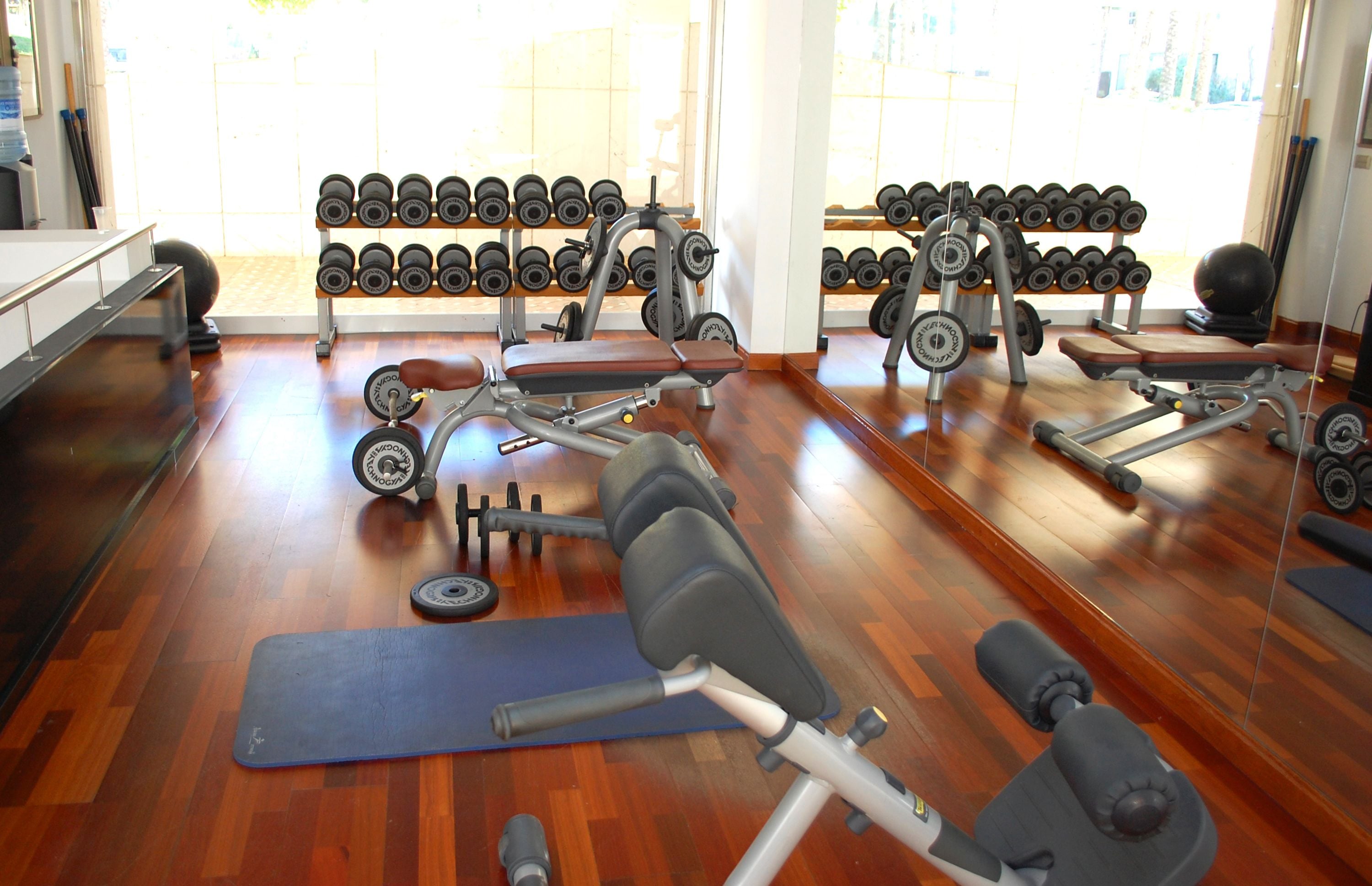 A gym with exercise equipment, dumbbells, and a blue mat.