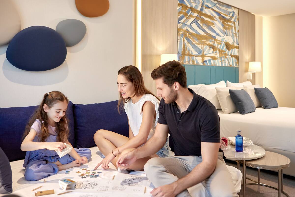 Ein modernes Hotelzimmer mit einem blauen Sofa, einem runden Couchtisch und einem großen abstrakten Gemälde an der Wand.