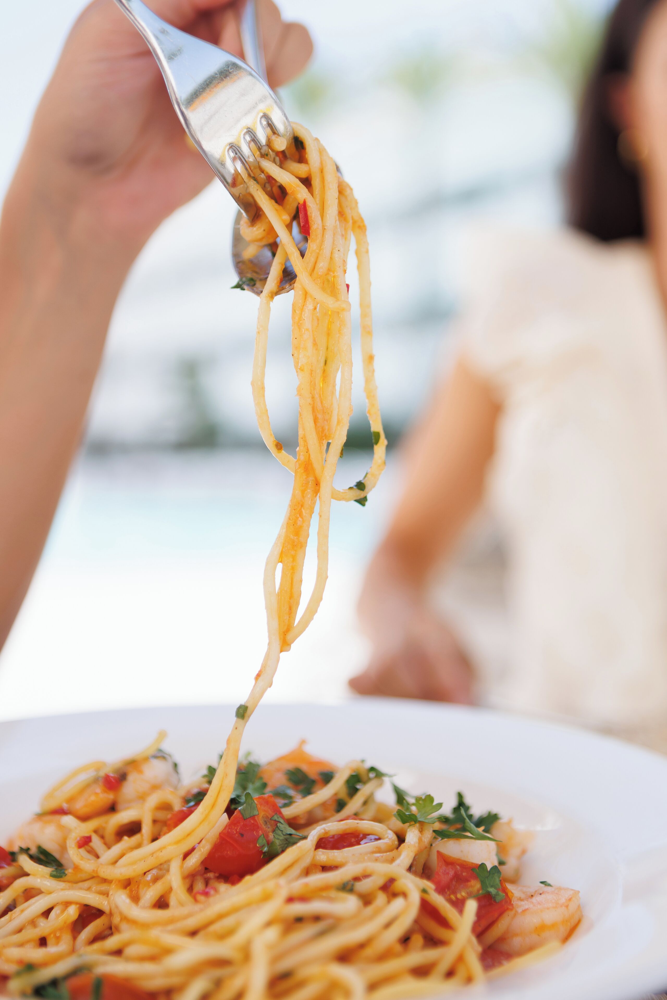 A close-up of a fork lifting spaghetti from a plate, indicating a meal setting.