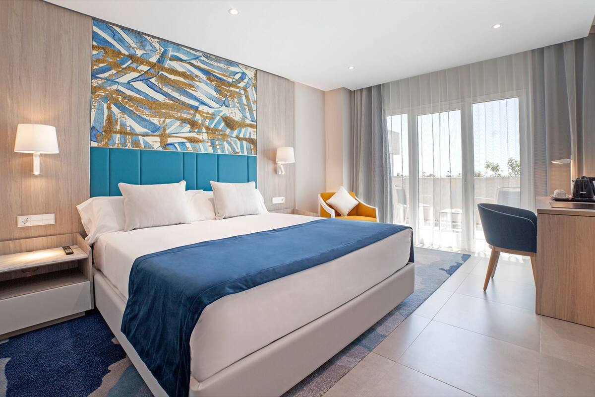 Ein modernes Hotelzimmer mit einem großen Bett, einem Schreibtisch und Blick ins Freie.