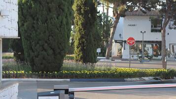 Een verhard gebied met een stopbord, een hoge boom en een gebouw met een bord waarop 'NOBU' staat.