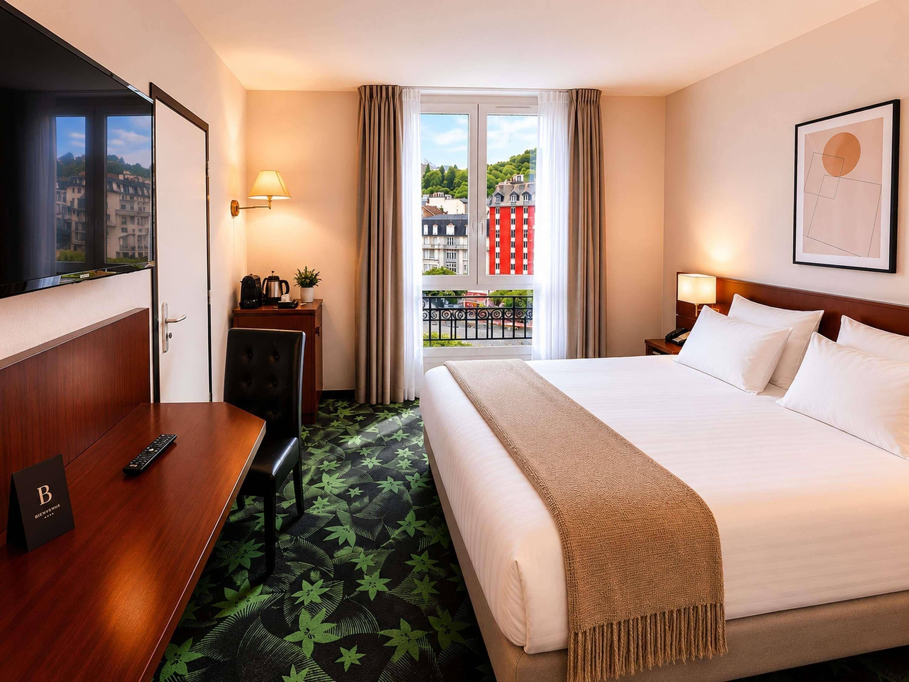 Une chambre d’hôtel comprenant un lit, un bureau, une chaise, une télévision, un balcon avec vue sur les bâtiments et une porte.