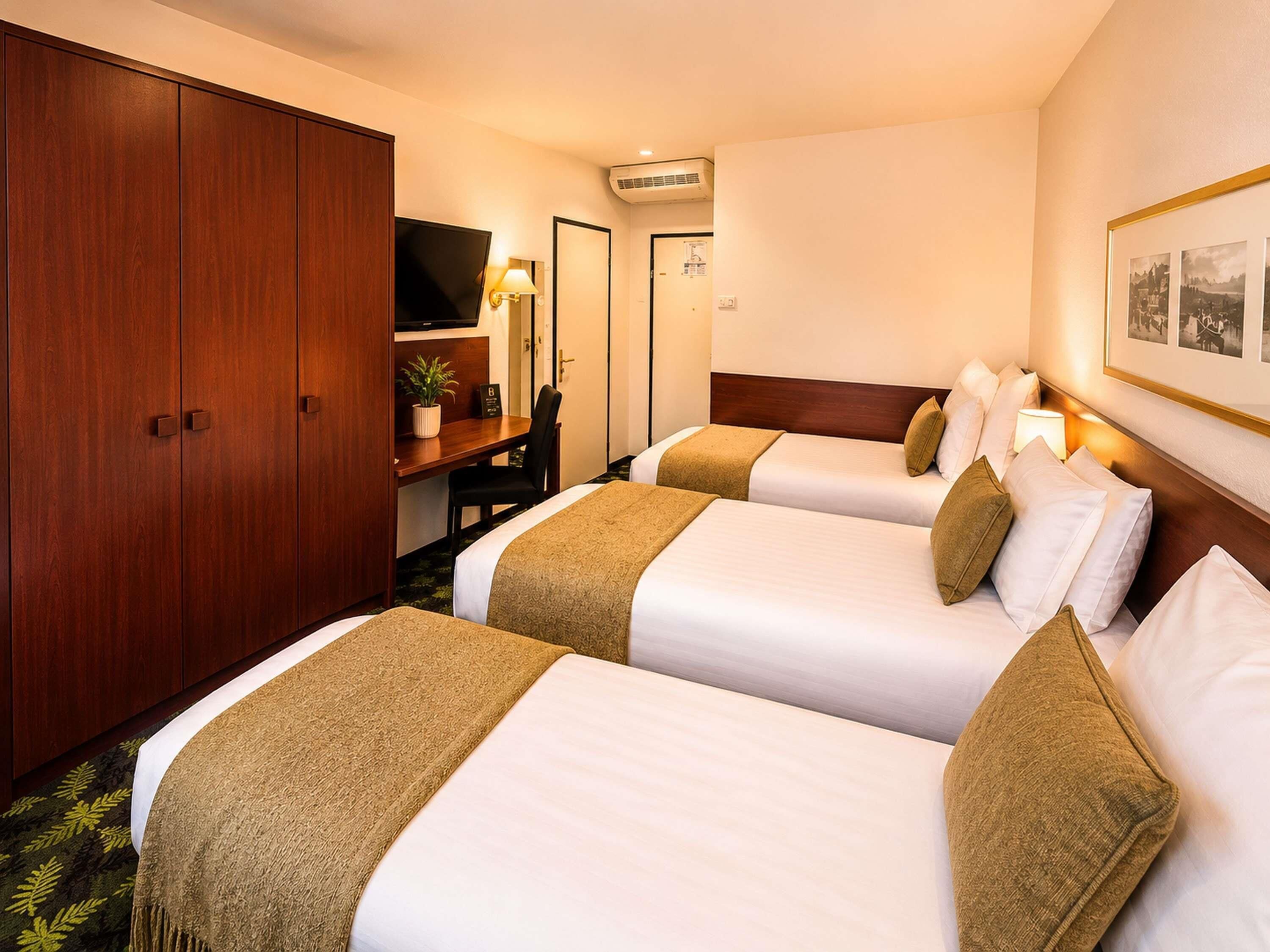 A hotel room with two beds, a desk, a TV, and a wardrobe.