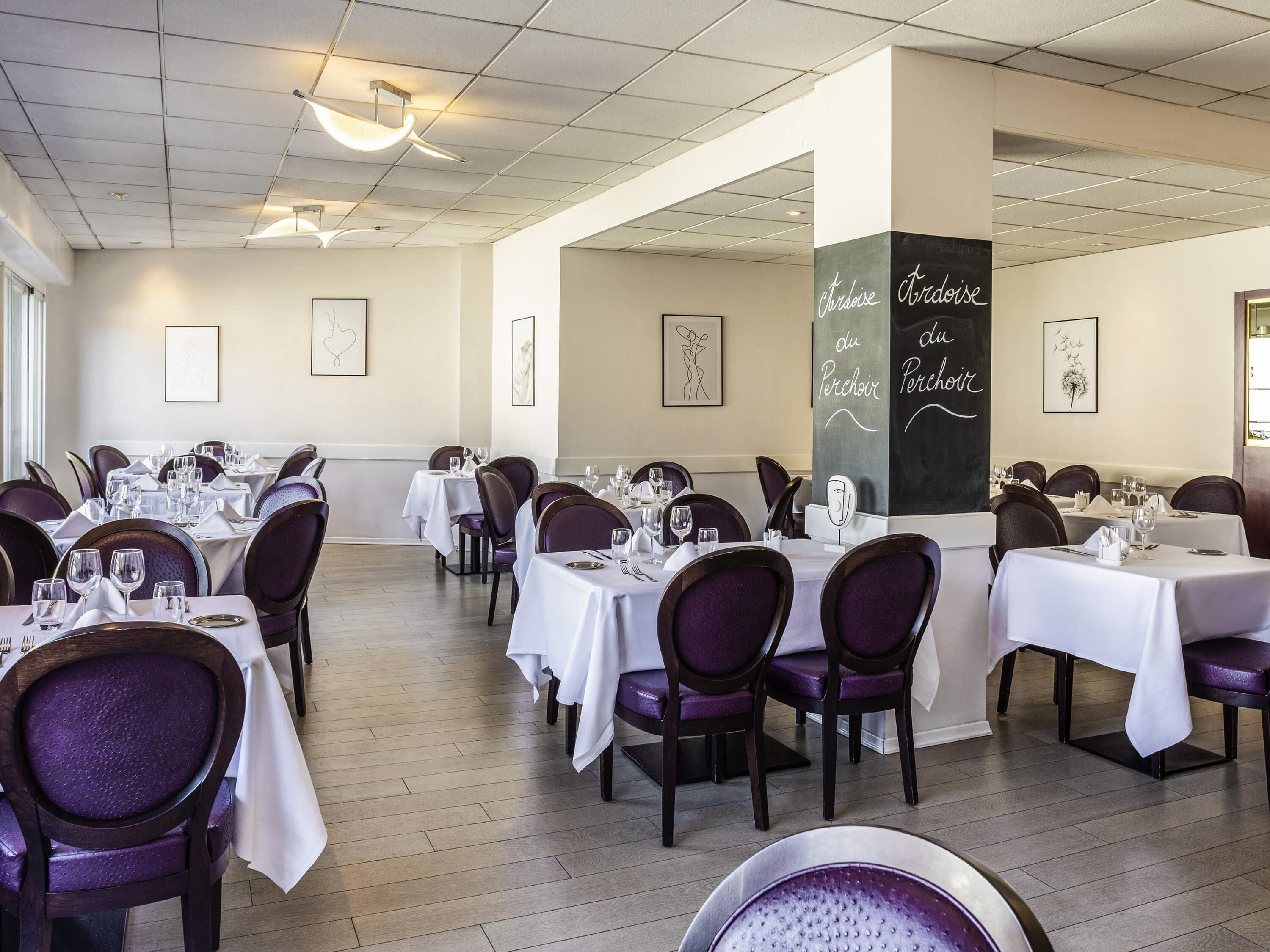 A restaurant with tables set for dining, framed artwork on the walls, and a chalkboard menu.