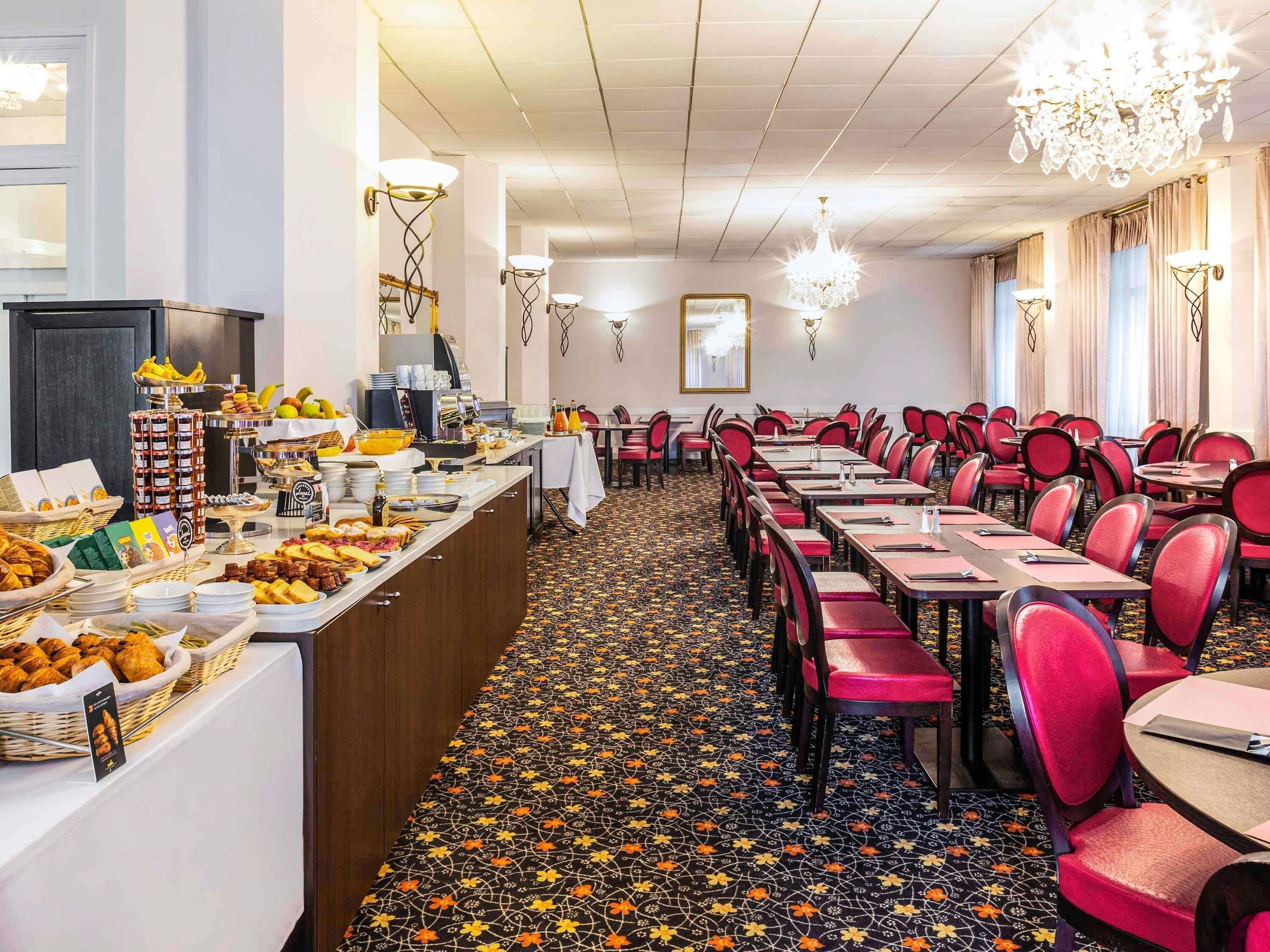 A hotel dining area with a buffet, multiple tables, and chairs.