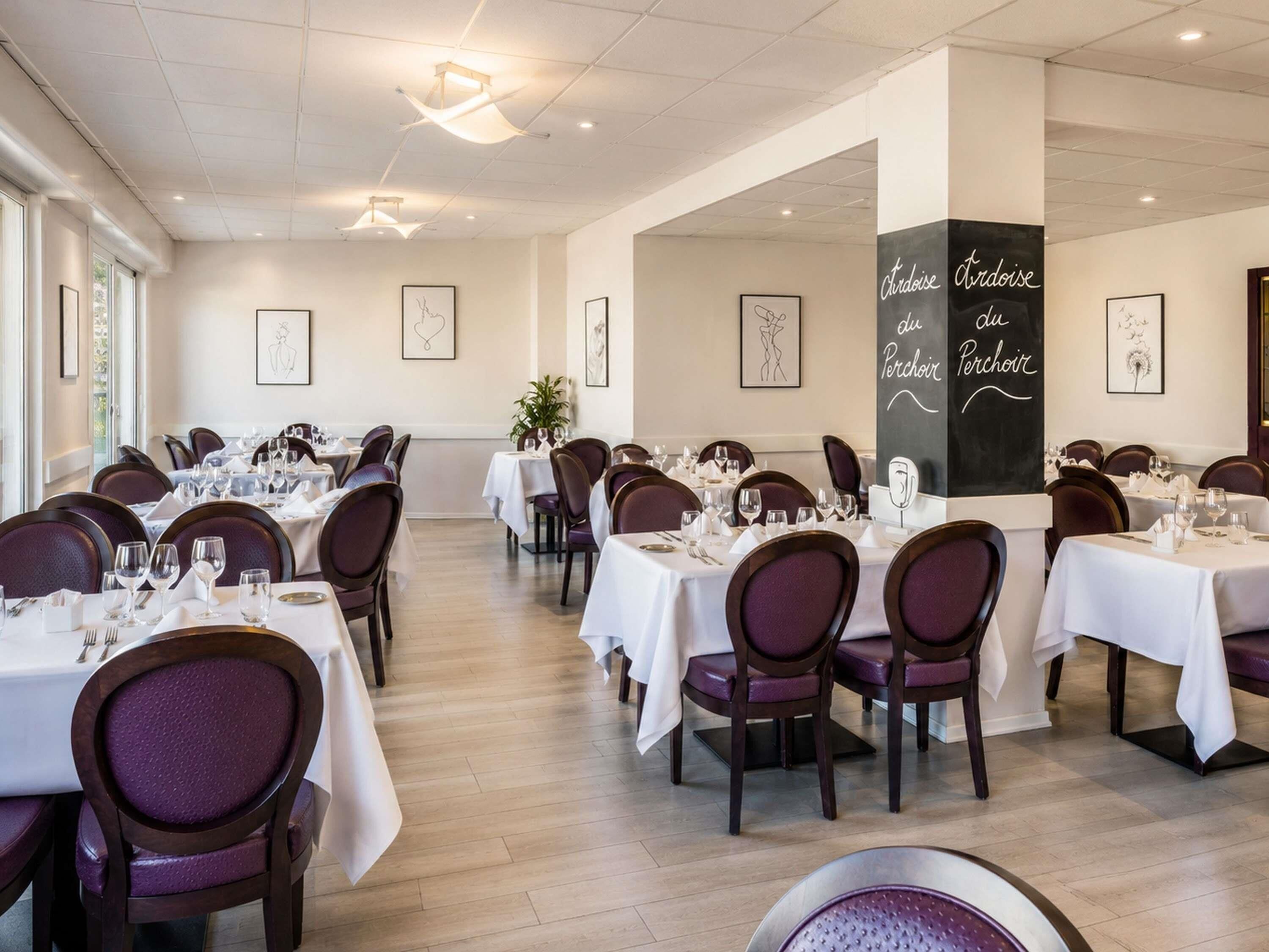 A restaurant with multiple tables, chairs, and framed artwork on the walls.