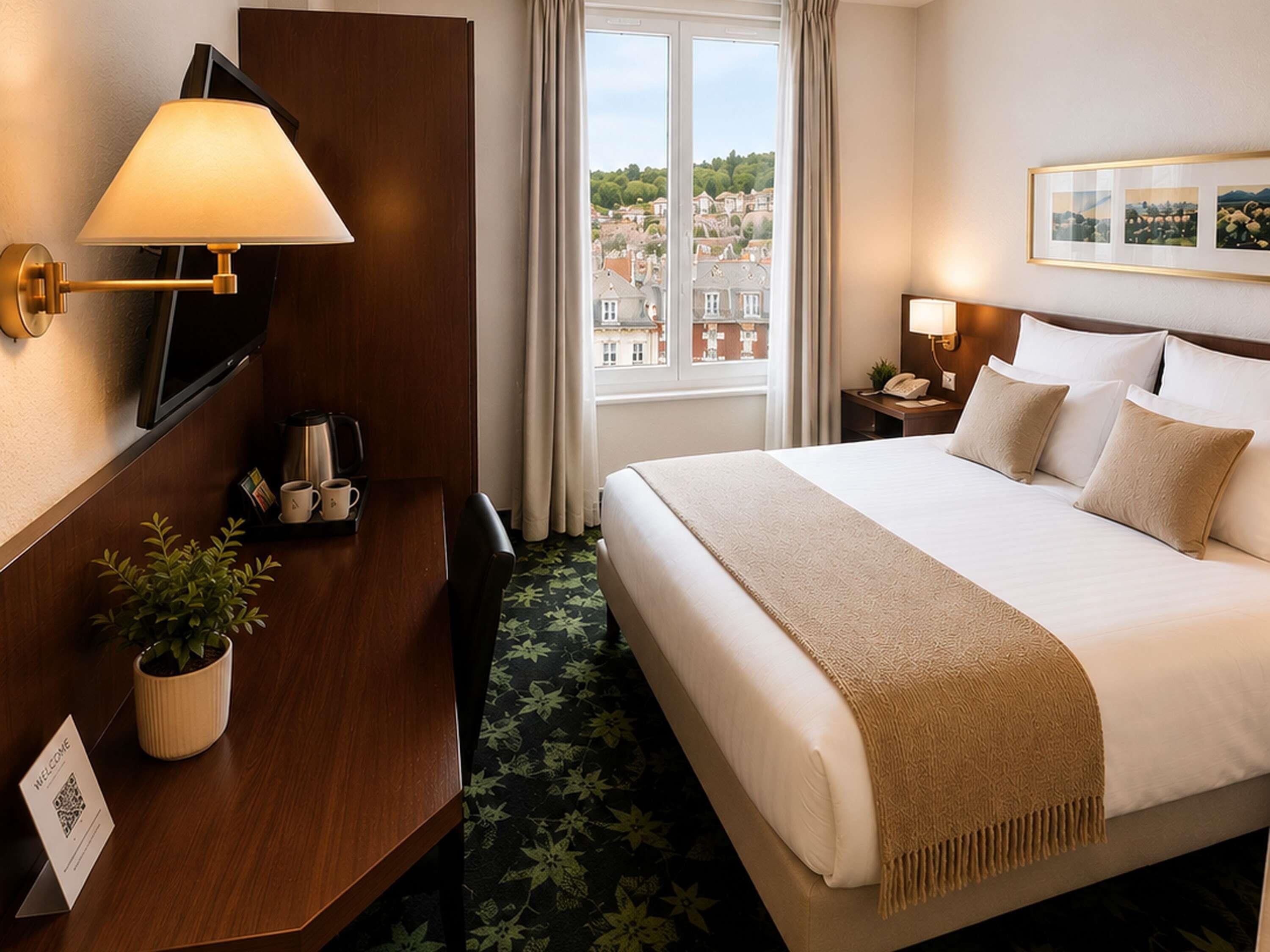 Habitación de hotel con cama, escritorio con cafetera, televisor, ventana con vista a la ciudad y un cuadro en la pared.