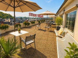 A rooftop terrace with outdoor seating, potted plants, and umbrellas. - Mercure Lourdes Imperial (Lourdes)