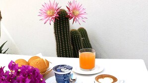 Una mesa con desayuno que incluye pan, una bebida, una taza de café y un recipiente con yogur.