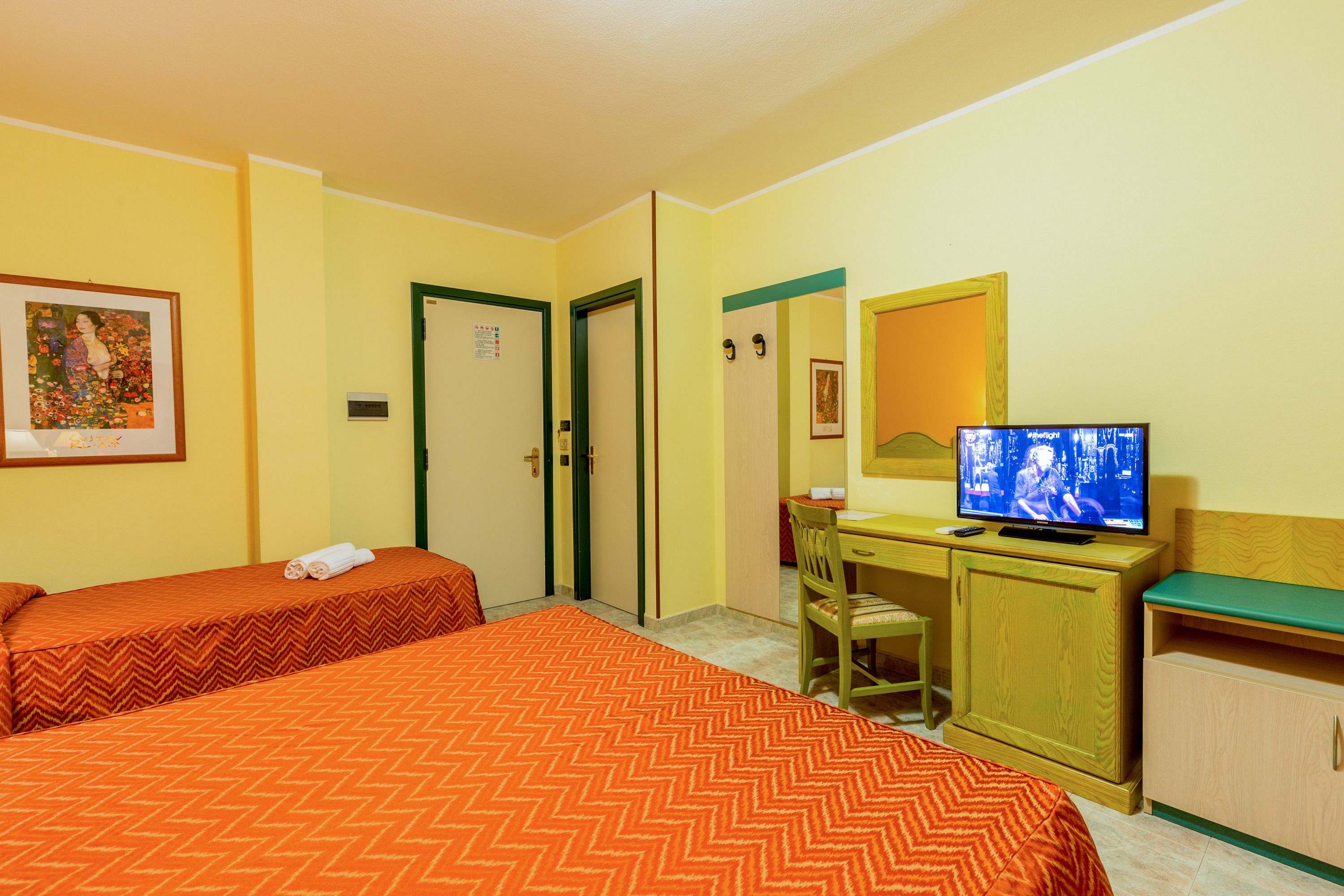 Une chambre d’hôtel avec deux lits, un bureau, une t élévision et un miroir.