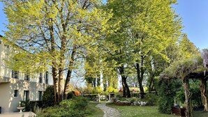 A garden pathway leading to a building with a stone facade and a pergola with climbing plants. - Hotel All'Orso (Roncade)