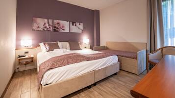 Una habitación de hotel con una cama, una silla, un escritorio y obras de arte en la pared.