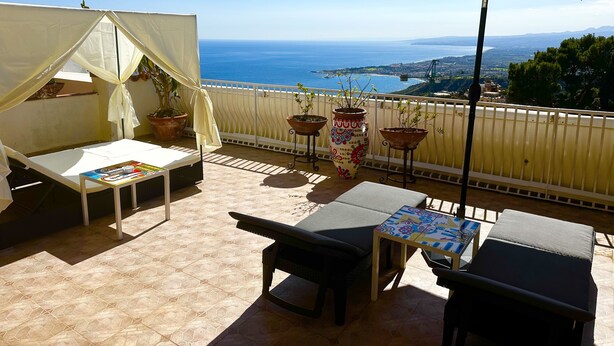 A balcony with a bed, a table, and potted plants. - Hotel Villa Greta (Taormina)