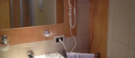 A bathroom with a sink, mirror, hairdryer, and towel rack.