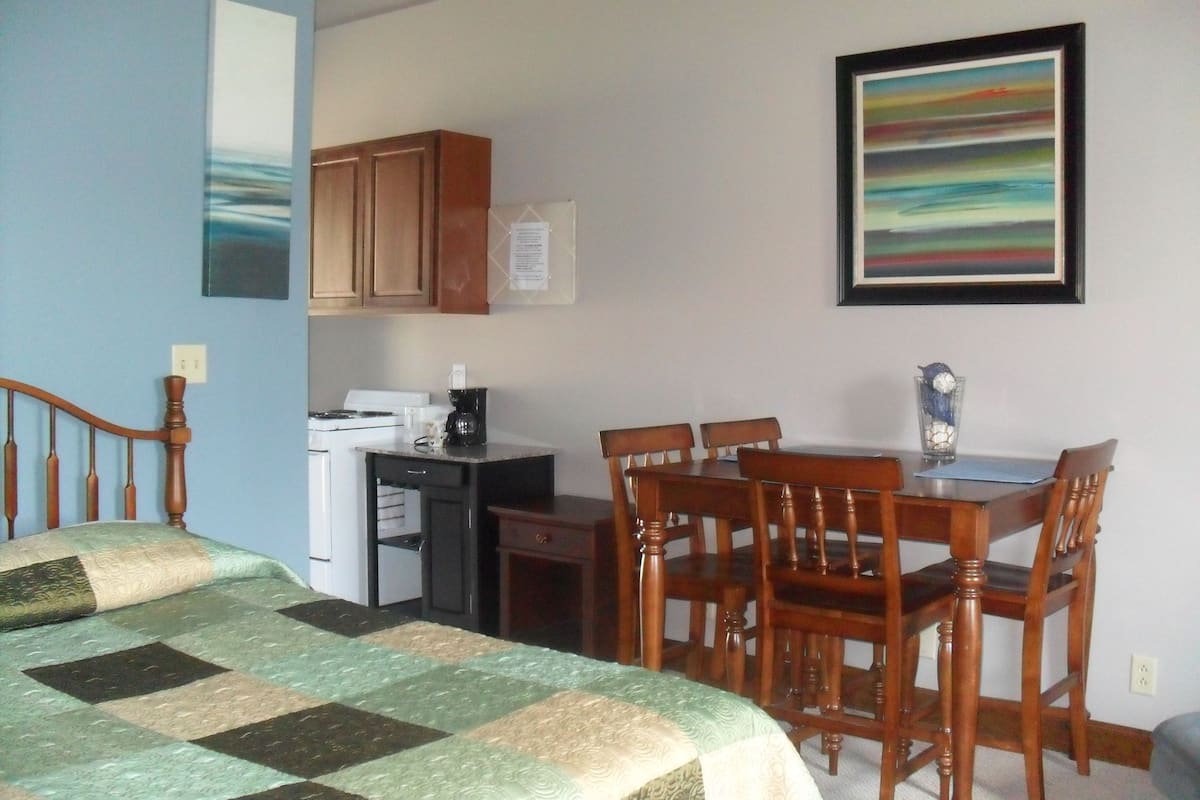 Una habitación con cama, escritorio, silla y mesa de comedor.