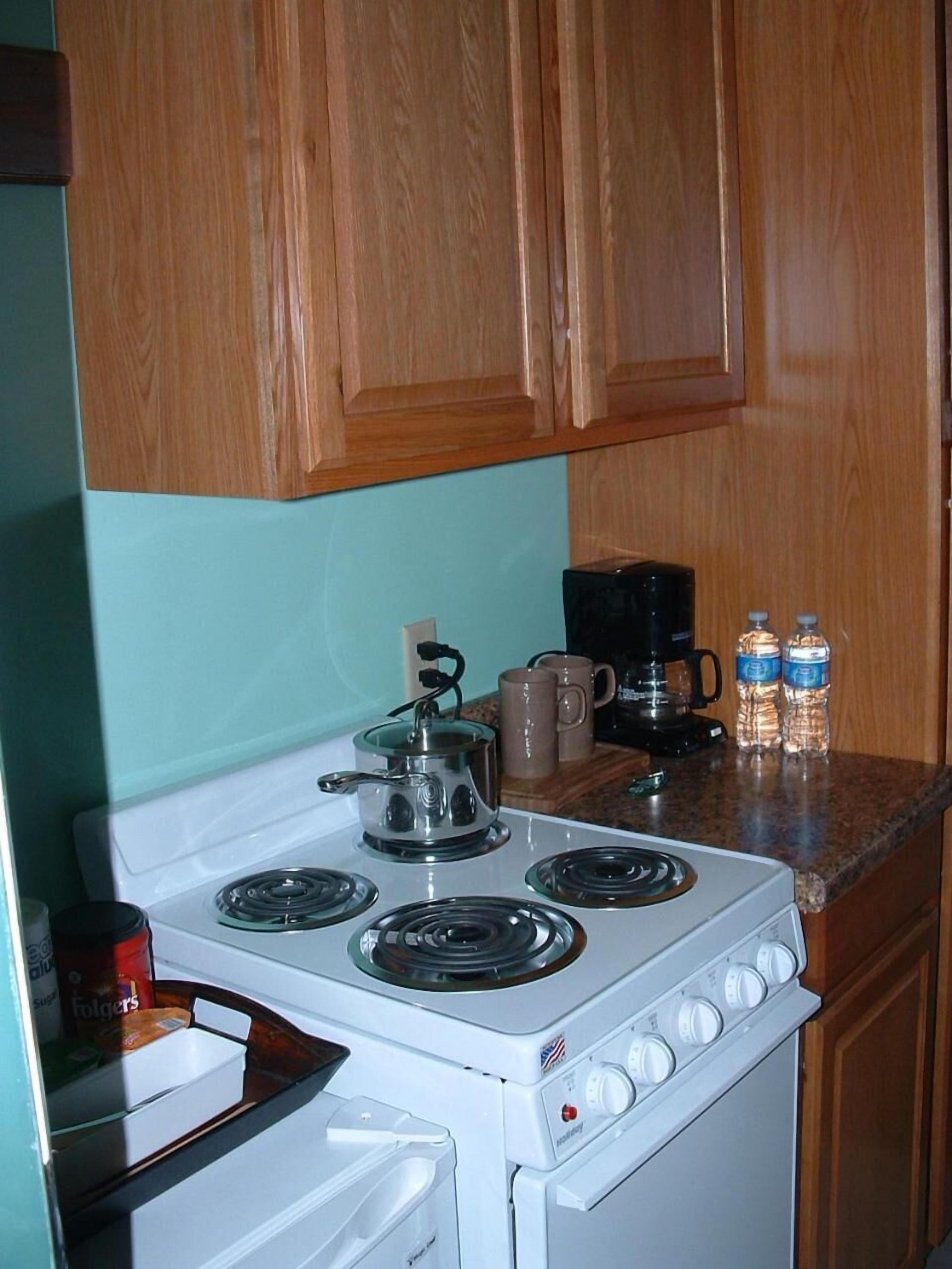 A kitchen with a white stove, wooden cabinets, and a coffee maker.