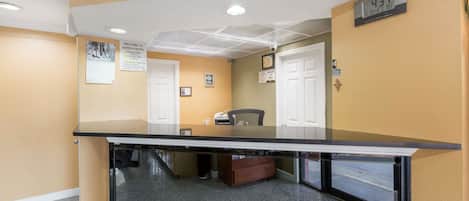 A reception area with a glass counter, a chair, and a clock on the wall.