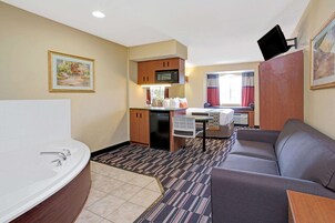 Una habitación de hotel compacta con baño, kitchenette y sofá.