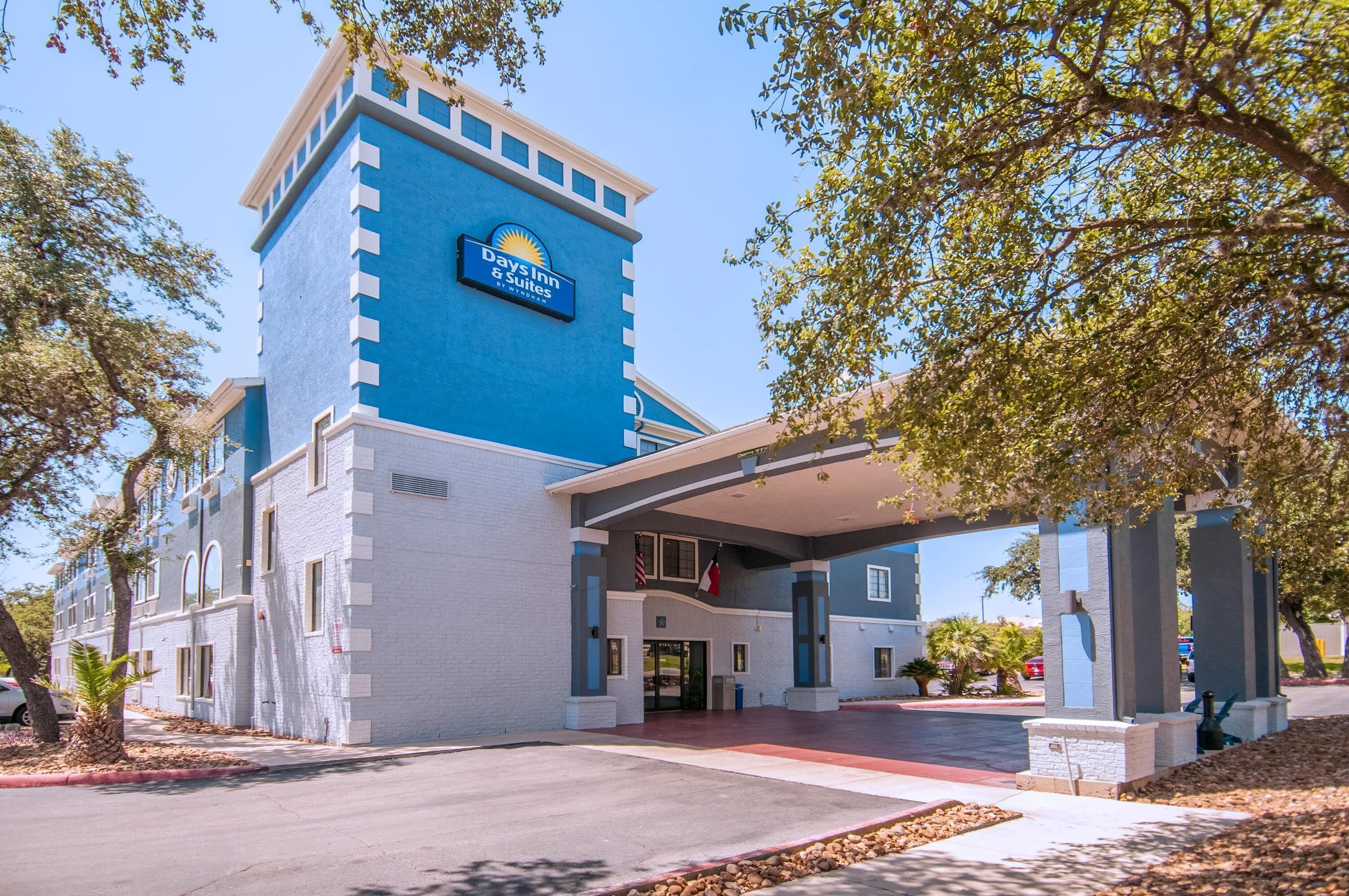 A Days Inn & Suites building with a blue facade, a covered entrance, and a parking lot.