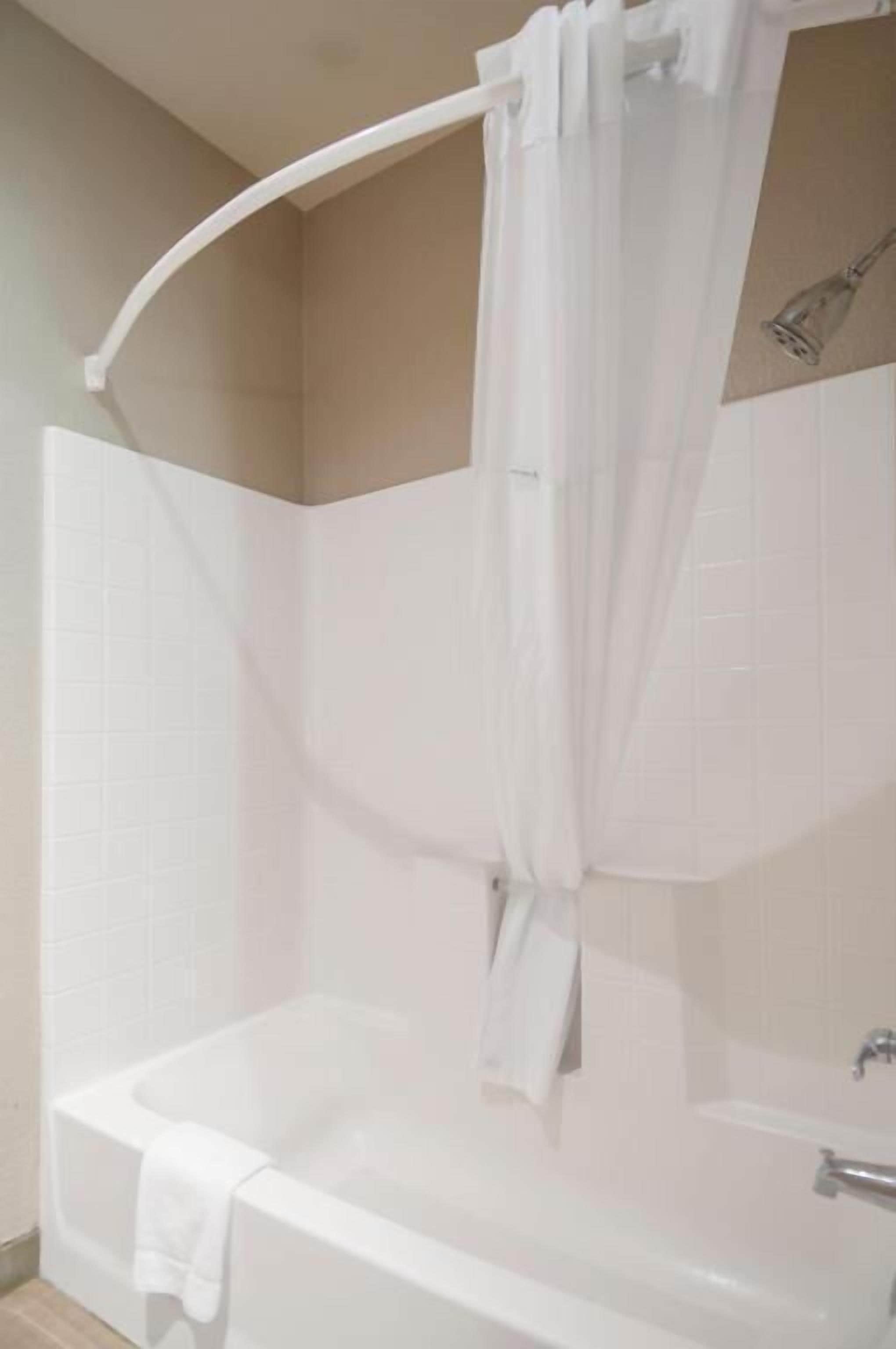 A bathroom with a bathtub, a shower curtain, and a towel.