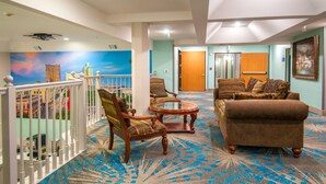 A hotel lobby with a balcony, seating area, and a door leading to another room.